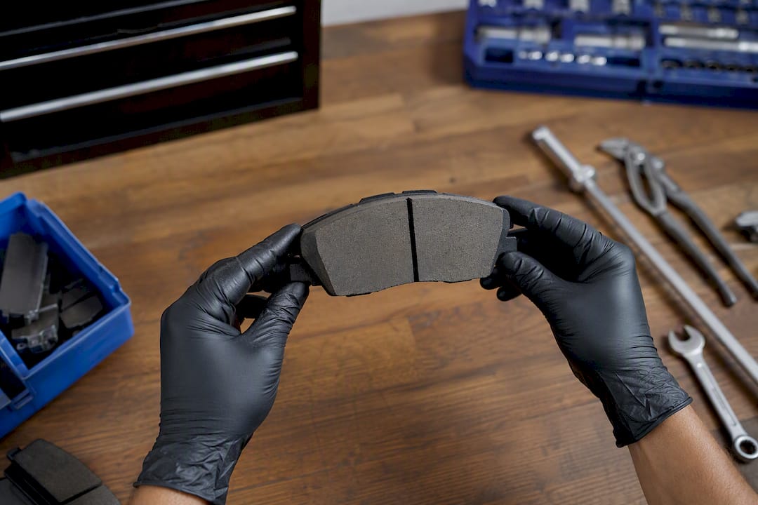 Hands holding ceramic brake pad near rotor