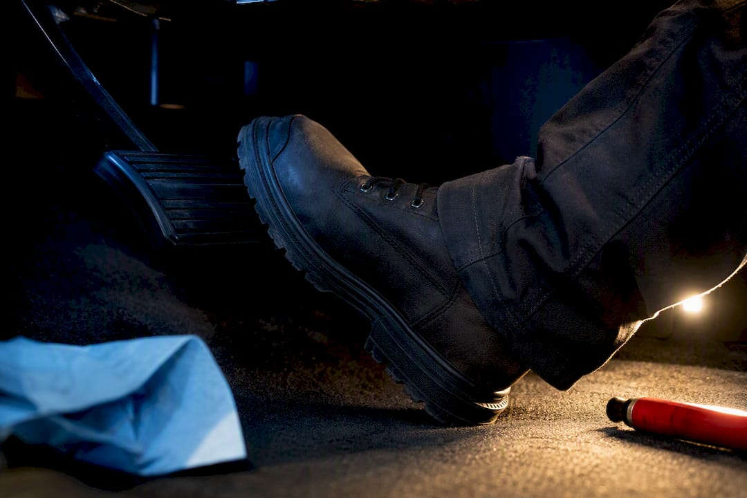Foot testing brake pedal travel in service bay