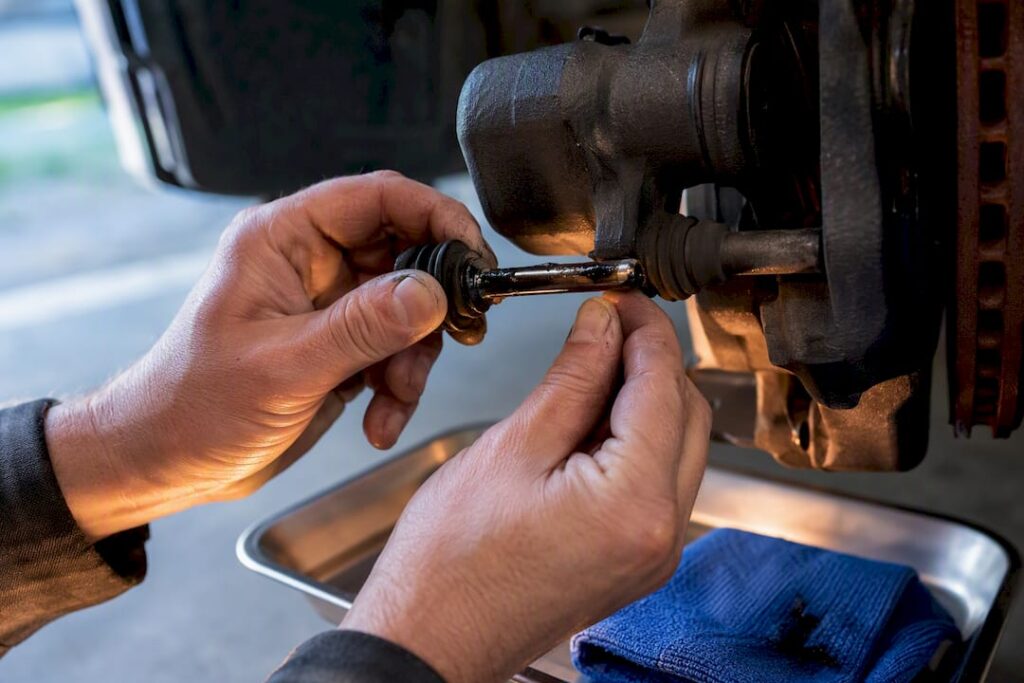 Hands removing a brake caliper slide pin