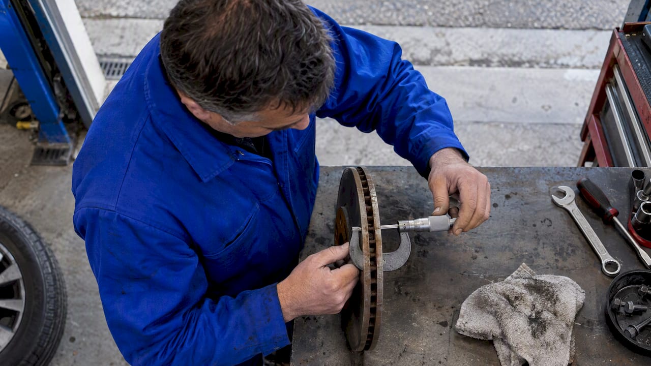Mechanic measuring brake rotor thickness